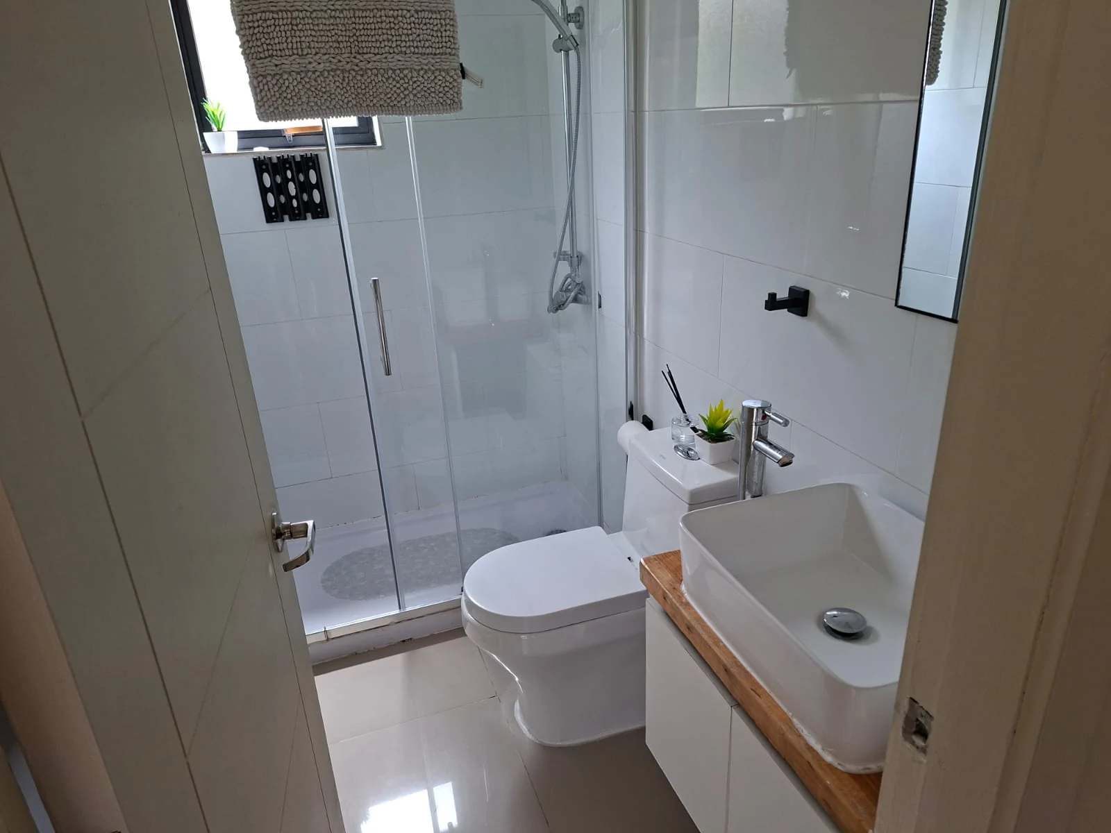 Baño de Casa Lavanda con ducha de vidrio, inodoro y lavamanos sobre mueble de madera